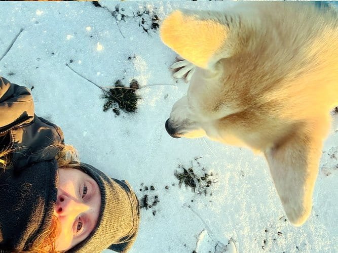 Young girl and dog playing in snow, emphasizing indoor pet activities and safety during winter storms in DFW.
